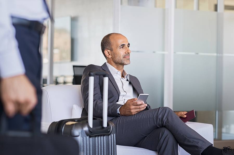 A picture of a bald man sitting and waiting for his flight