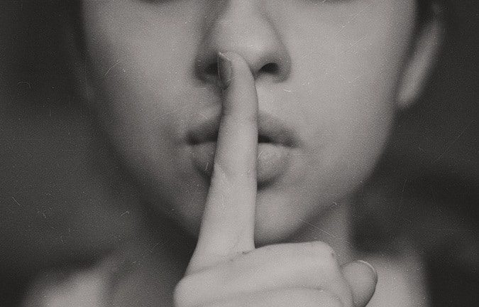 A woman with her finger on her lips as if shushing someone