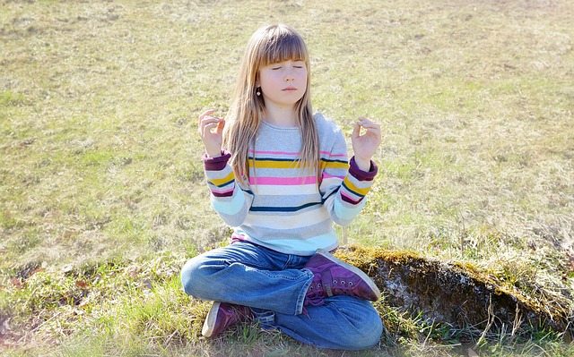 A small girl meditating on a field