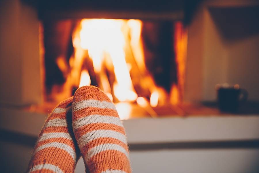 A picture of a person wearing socks and sitting by the fireplace