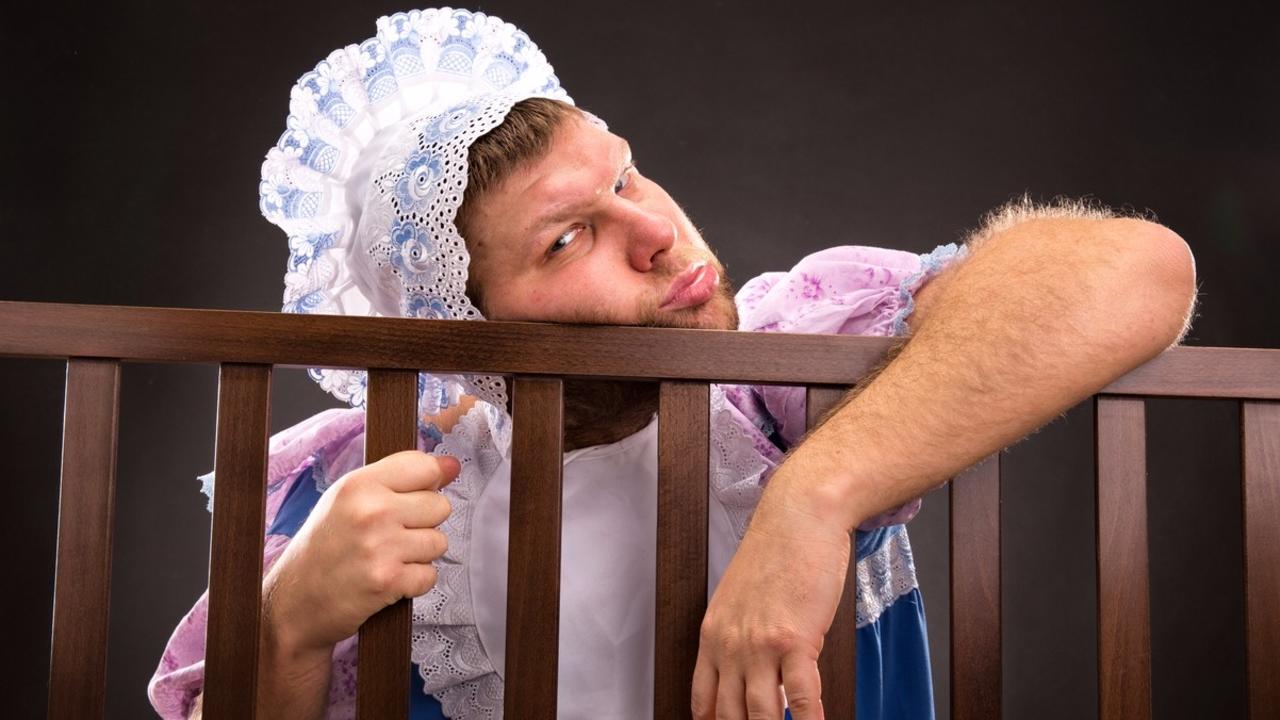 an adult man dressed as a baby in a crib