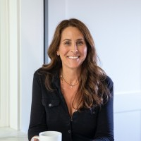 A woman holding a cup of coffee smiling for the camera.