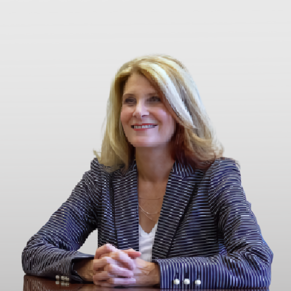 A woman sitting at a table with her hands crossed.