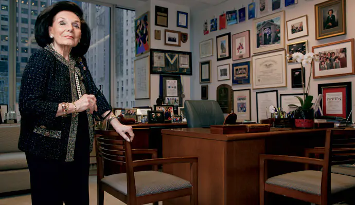 A picture of a woman standing near her desk with her achievement