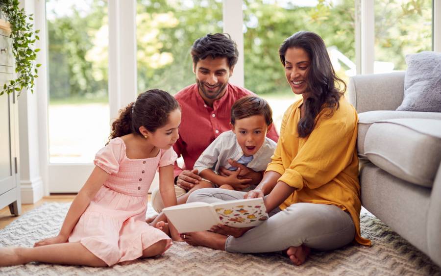 A family sitting on the floor, reading a book together