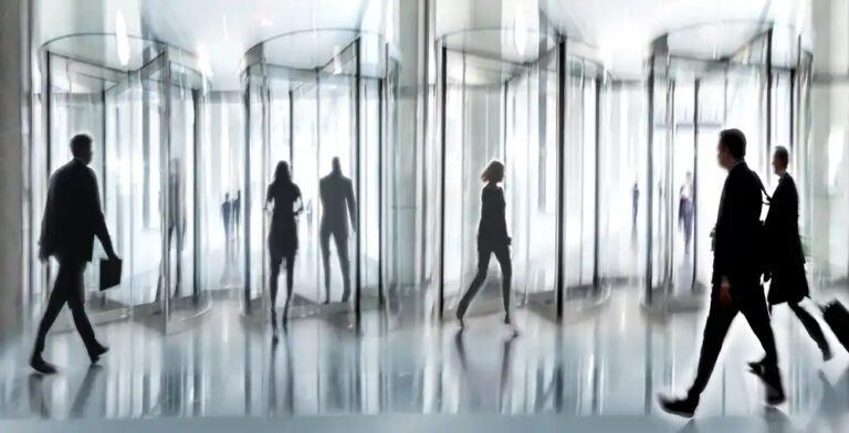 A group of people walking in front of glass walls.