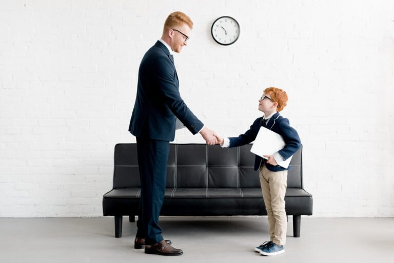 A man and boy shaking hands in front of a couch.