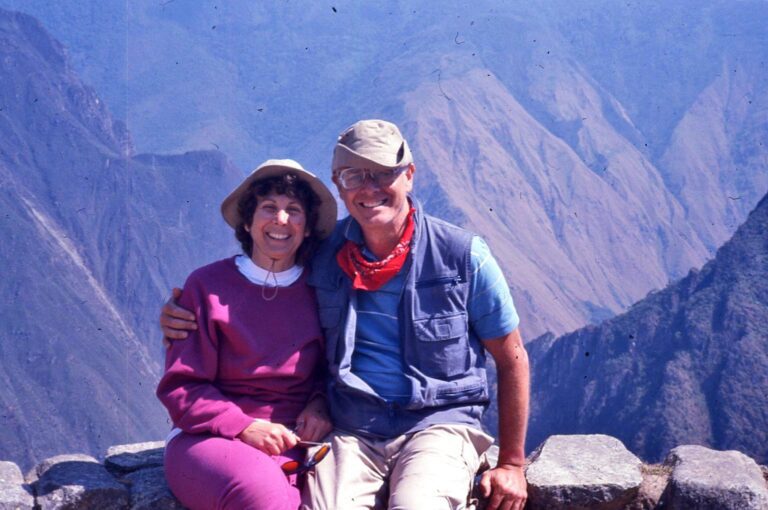 A man and woman sitting on top of a mountain.