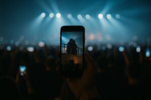 Smartphone recording of a crowd capturing a silhouetted couple in a concert balcony, symbolizing public scrutiny in the CEO-HR scandal
